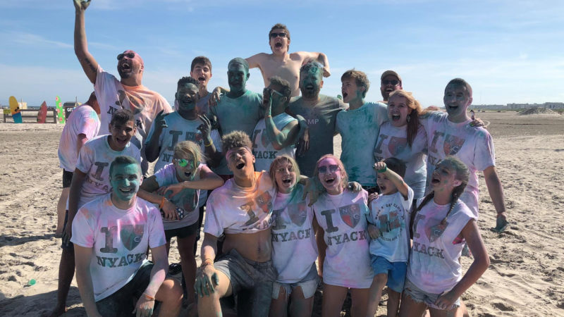 A Group of Teens Laughing in colorful shirts on the beach