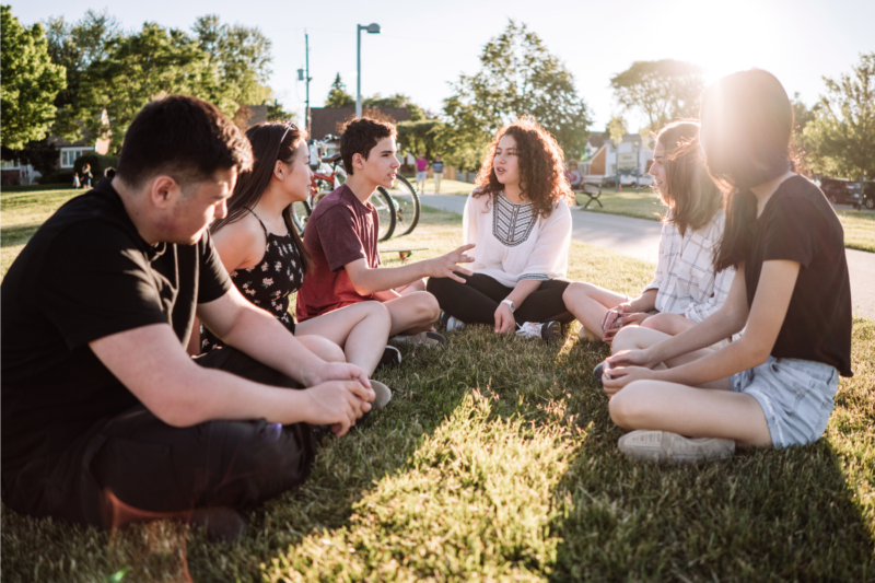 A Group of Teenagers Sitting In a circle on the grass